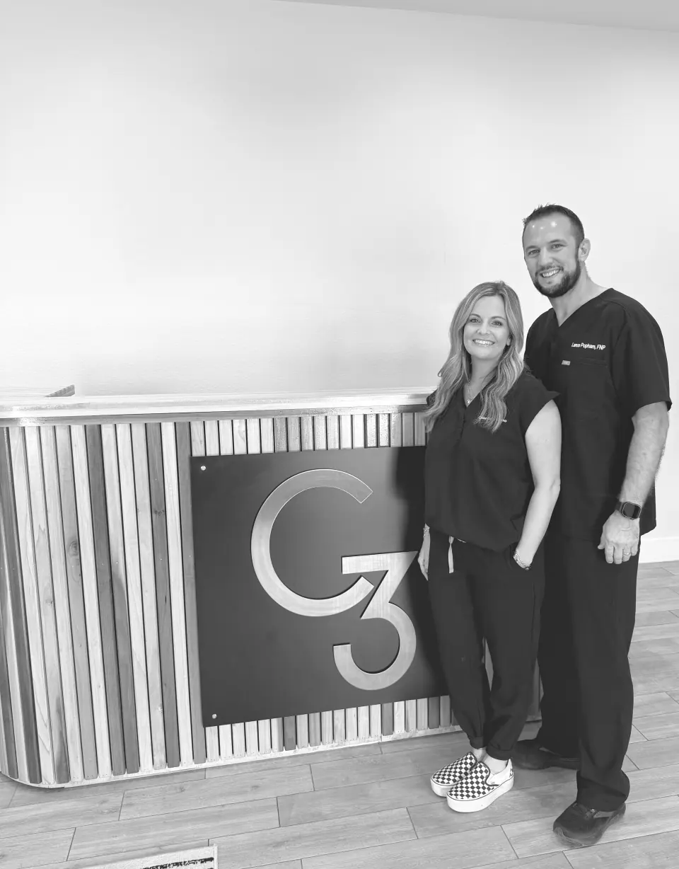 Lance and Brennan Popham standing beside the C3 monogram on the studio's front desk
